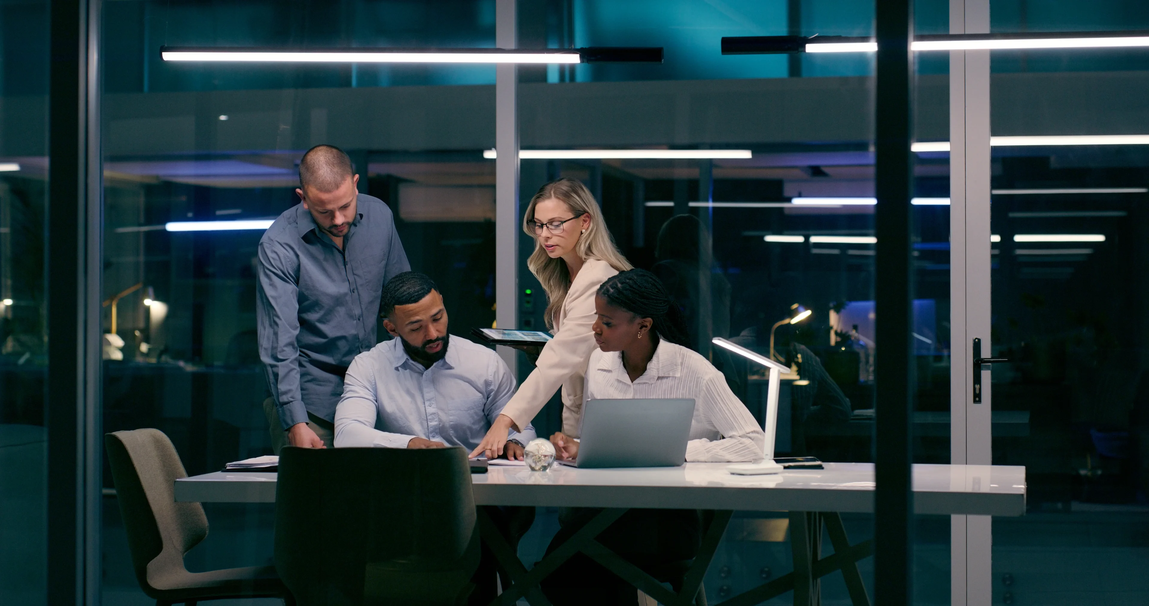 Team collaborating on a project in a modern office at night.